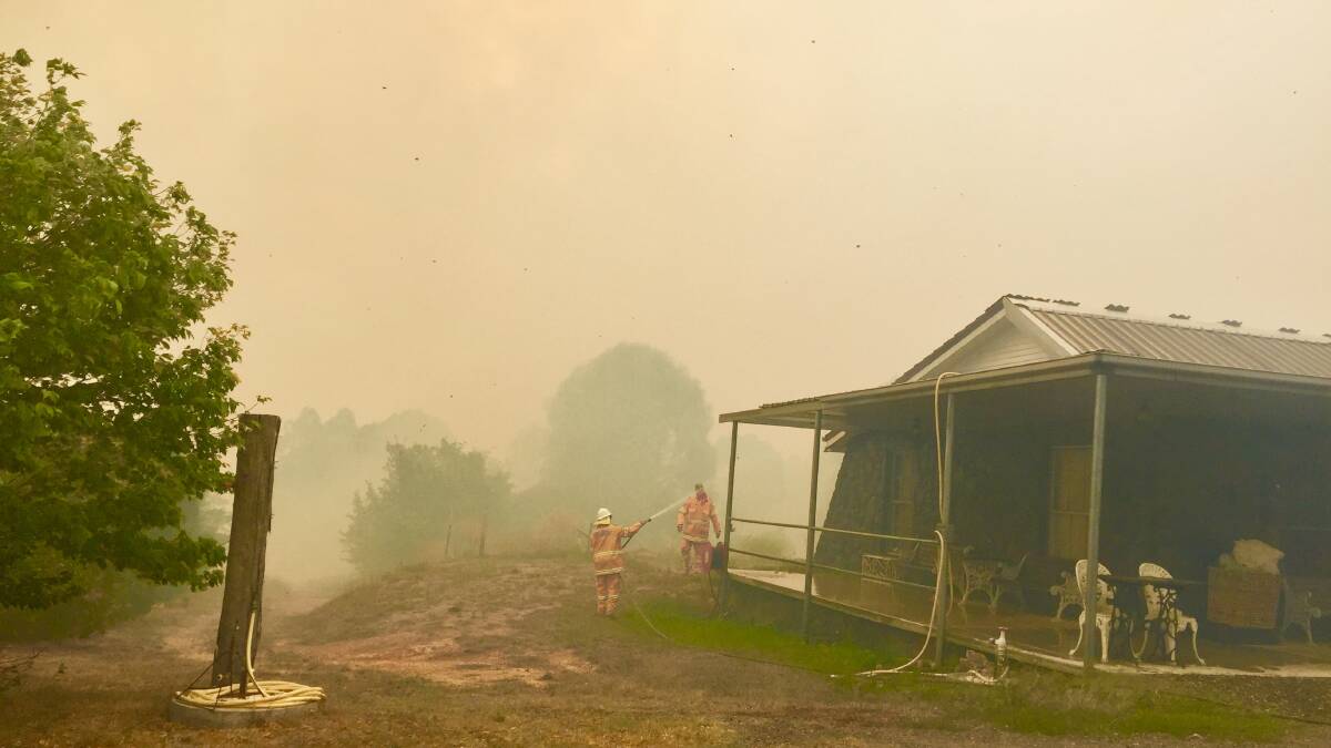 Firefighters keep the blaze from engulfing a house. Photo: Jessica Cole.