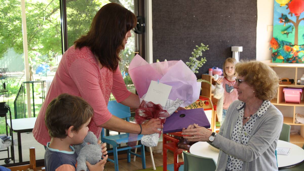 YECCA board vice president Maree Doyle and son Xavier present Margot Gregory with flowers and chocolates in appreciation for 25 years of service.