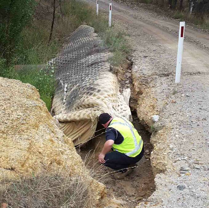 ROAD TO RECOVERY: A Roads and Maritime Services officer inspects flood damage on Berrebangalo Road, one of many damaged by rainfall in 2016. Photo: Supplied