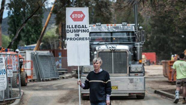 Protest organiser John Connelly stops a moving truck outside the ANU construction site. Photo: Karleen Minney