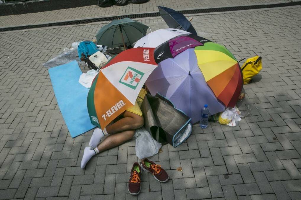 A student protester sleeps under umbrellas during a quiet moment at a protest site in Hong Kong. Photo: Paula Bronstein/Getty Images