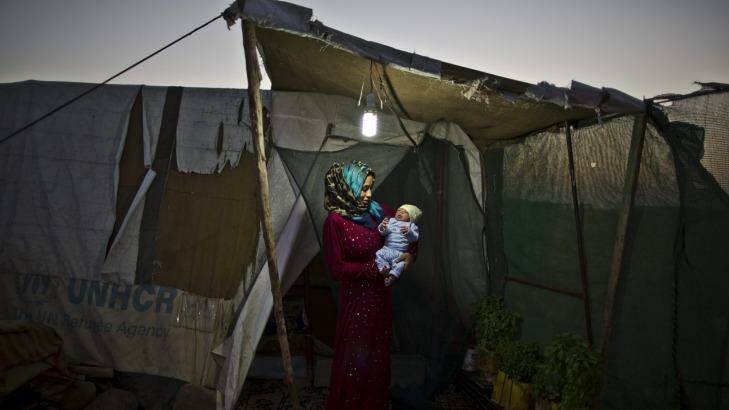 In this Saturday, Aug. 1, 2015 photo, Syrian refugee Huda Alsayil, 20, holds her newborn son Mezwid, 7 days, inside her tent at an informal tented settlement near the Syrian border, on the outskirts of Mafraq, Jordan. Photo: AP