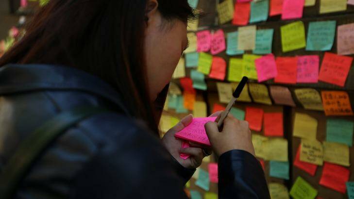 A woman from Hong Kong, whose friends are part of the protest, writes a message of support to post on the walls of Hong Kong House Photo: Kate Geraghty