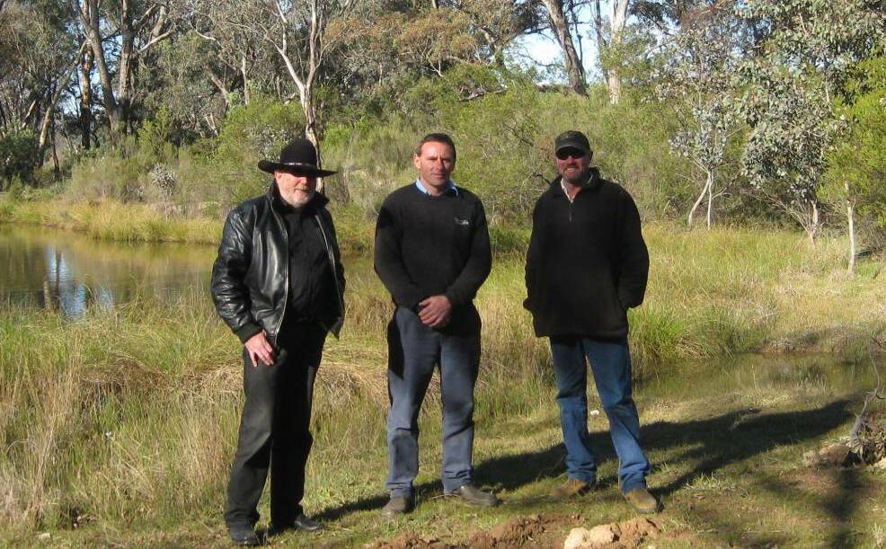 Upper Lachlan Shire councillor John Searl, senior biosecurity officer (south East LLS) Chris Harris and Dave Wiseman at the dam on Dalton's TSR near the ruts from illegal vehicle trespass in the foreground. Photo: Supplied.