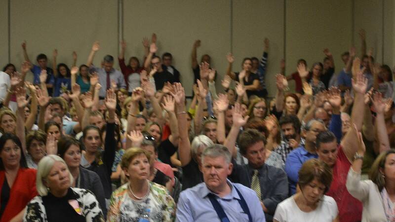 School community members raise their hands after being asked if they support the fight to keep Mt Carmel secondary school open for at least one more year.