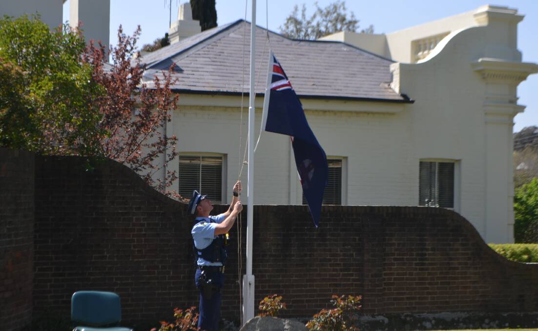 Senior Constable Jeremy Farr lowers the flag at the Remembrance Day ceremony on Monday.