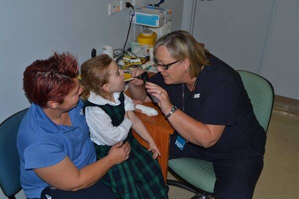 Teigan Farnell, aged five, has her throat examined by emergency nurse practitioner Wendy Waters while mum Kath Farnell looks on.