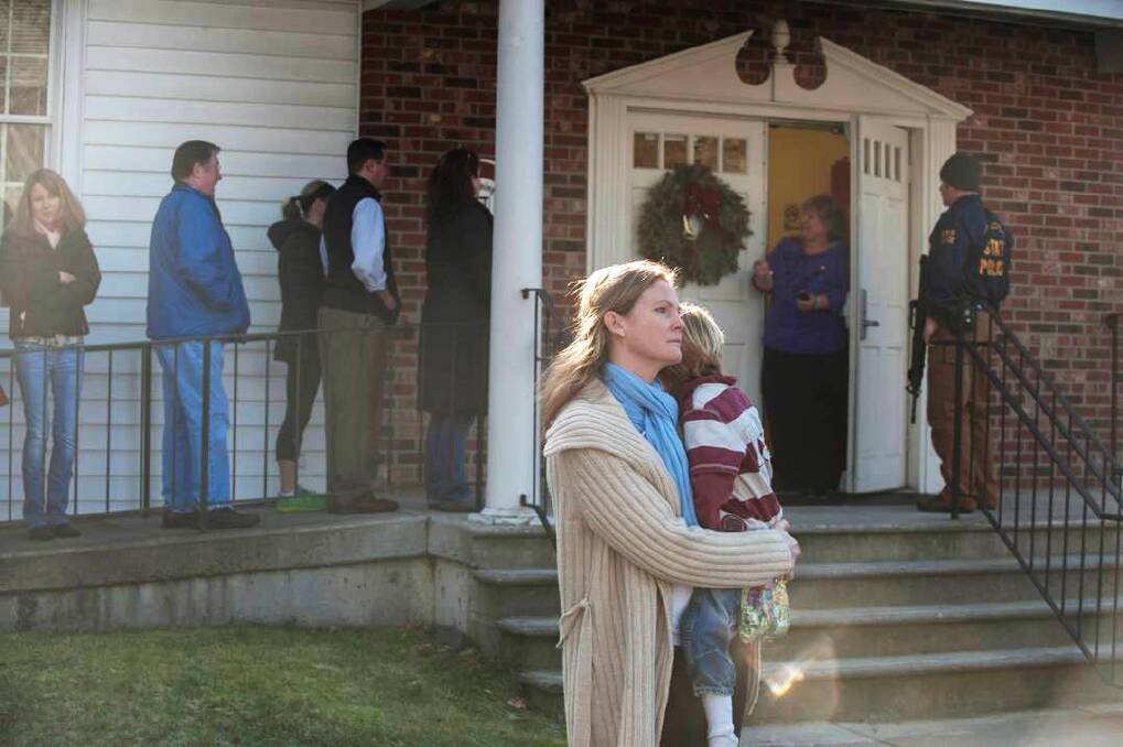 NEWTOWN, CT - DECEMBER 14: A woman holds a child as people line up to enter the Newtown Methodist Church near the the scene of an elementary school shooting on December 14, 2012 in Newtown, Connecticut. According to reports, there are about 27 dead, 18 children, after a gunman opened fire in at the Sandy Hook Elementary School. The shooter was also killed.