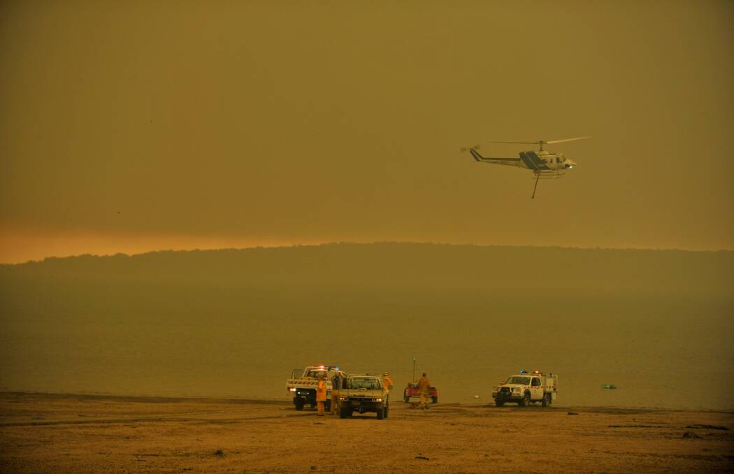 Fire fighters and water bombing helicopters fill up at Lake Glenmaggie. Photo: Michael Clayton-Jones