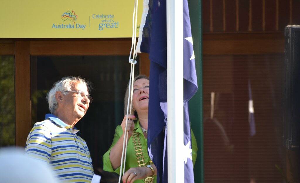 Eric Bell helps Rowena Abbey raise the Australian flag.
