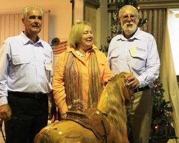 Jack Price, Rowena Abbey and Terry Hunt prepare to draw the winner of the rocking horse in the Menshed raffle.