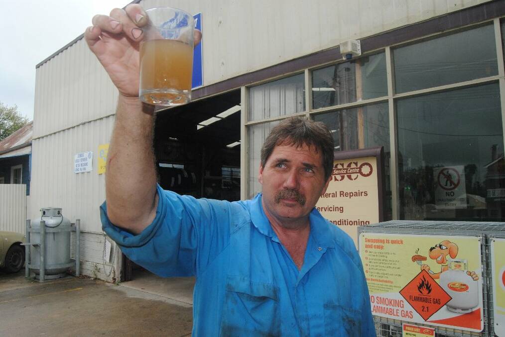 March: Gunning resident Jay Gribbin holds up a glass of brown muddy Gunning water. The town was faced with boil-water alerts for several months before the community was successful in attaining funding to build a new plant. Photo: Goulburn Post.