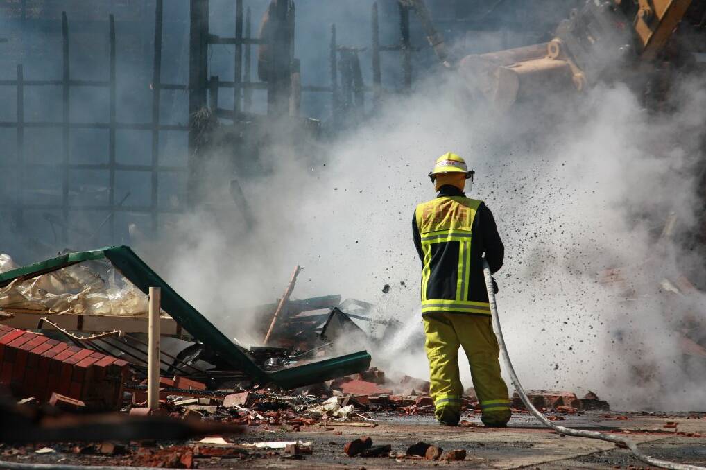 A Yass fire fighter douses the smouldering rubble on Saturday.