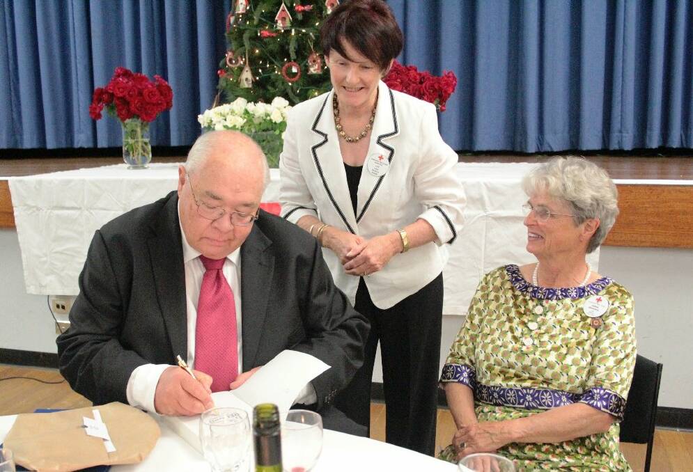 Laurie Oakes signs a book for the Red Cross’ secretary Nancye Lee, while president Anna Binning looks on.
