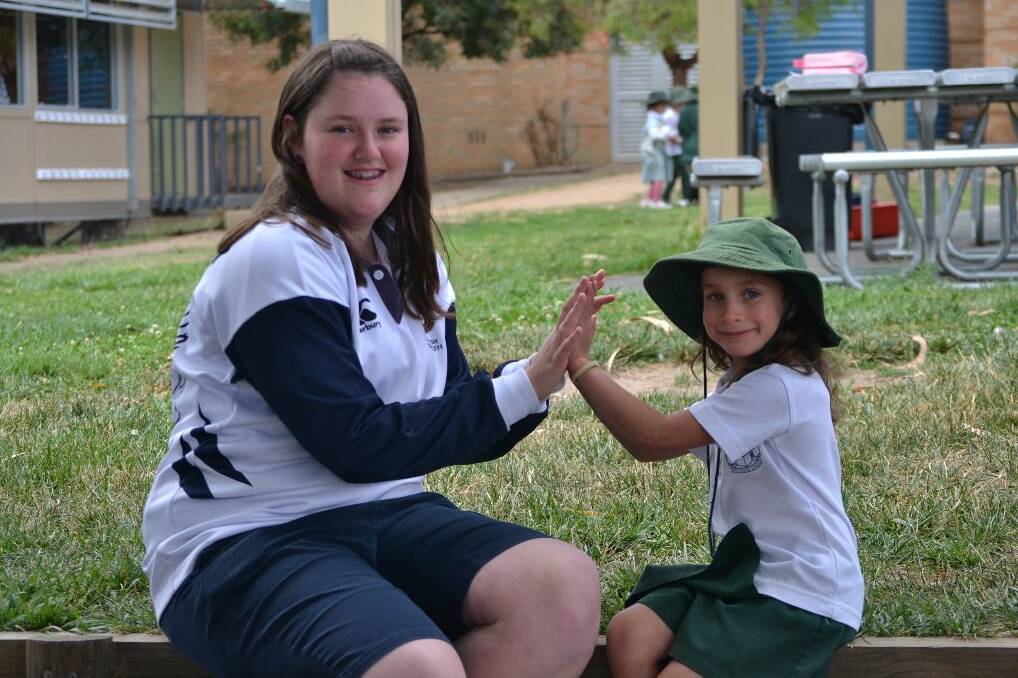 Yass High student Caitlyn Farmer plays a clapping game with year one student Astrid Roasario at berinba Primary School. 