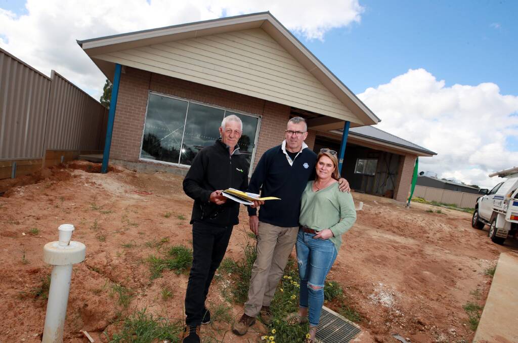Andrew White with Geoff and Cathy Reid in front of the house that is starting to take shape in Boorooma. Photo: Les Smith 
