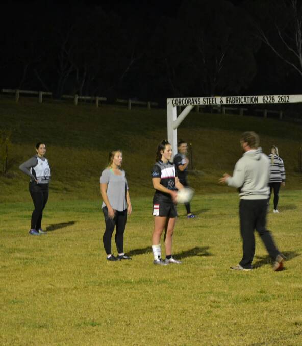 Let me show you something: Greenwood walks the team through a training drill, under the bright spotlights at Walker Park. Photo: Zac Lowe. 