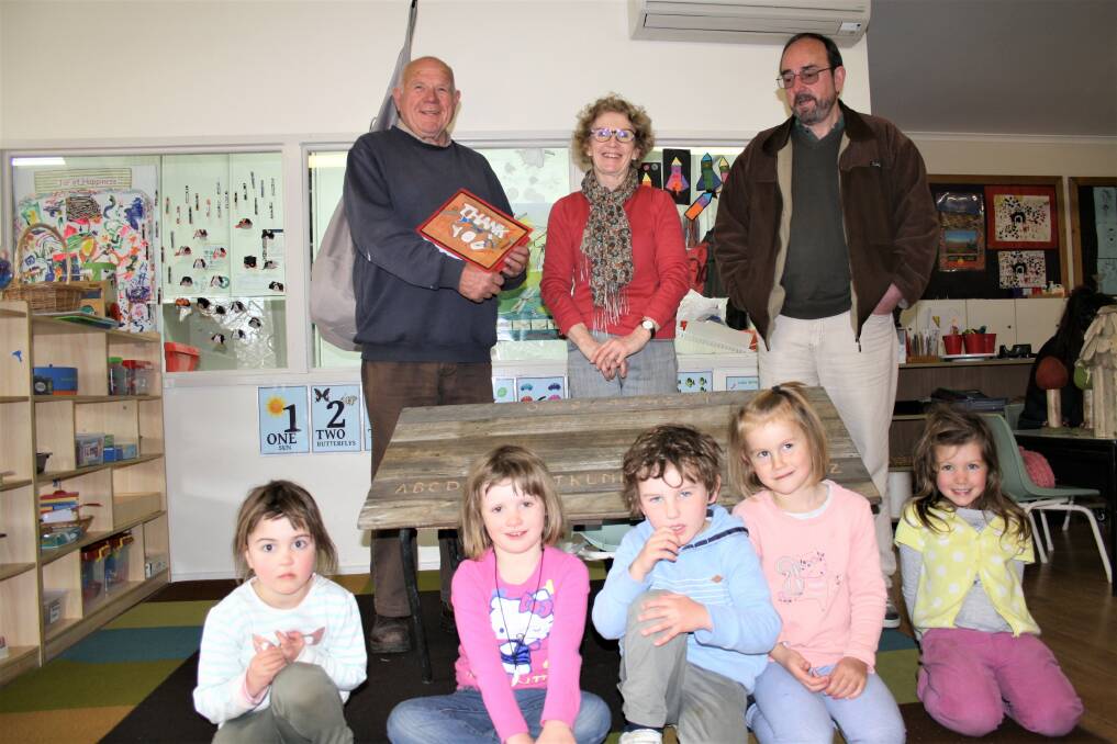 APPRECIATION: Men’s Shed members Ian McLean and Peter Roberts with one of the two tables restored for YECCA. Teacher Margot Gregory and preschoolers presented the Men’s Shed with a thank you card and donation. Photo: Alix Douglas