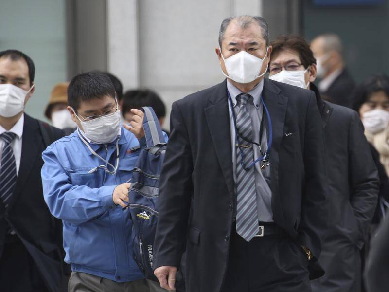 People wearing face masks to protect against coronavirus cross a street in Tokyo.