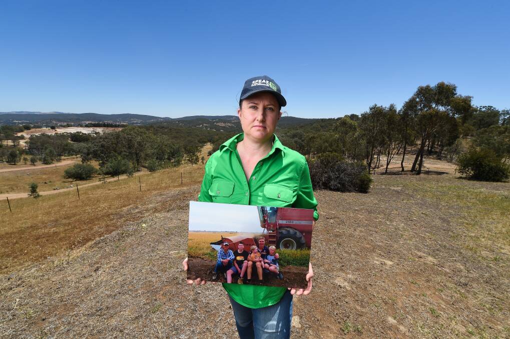 Shelley Scoullar holds a picture of her family - husband Paul and sons Hayden, 14, Lachie, 4, and Jack, 12 - taken in April 2019 during their last rice harvest on her farm. 
