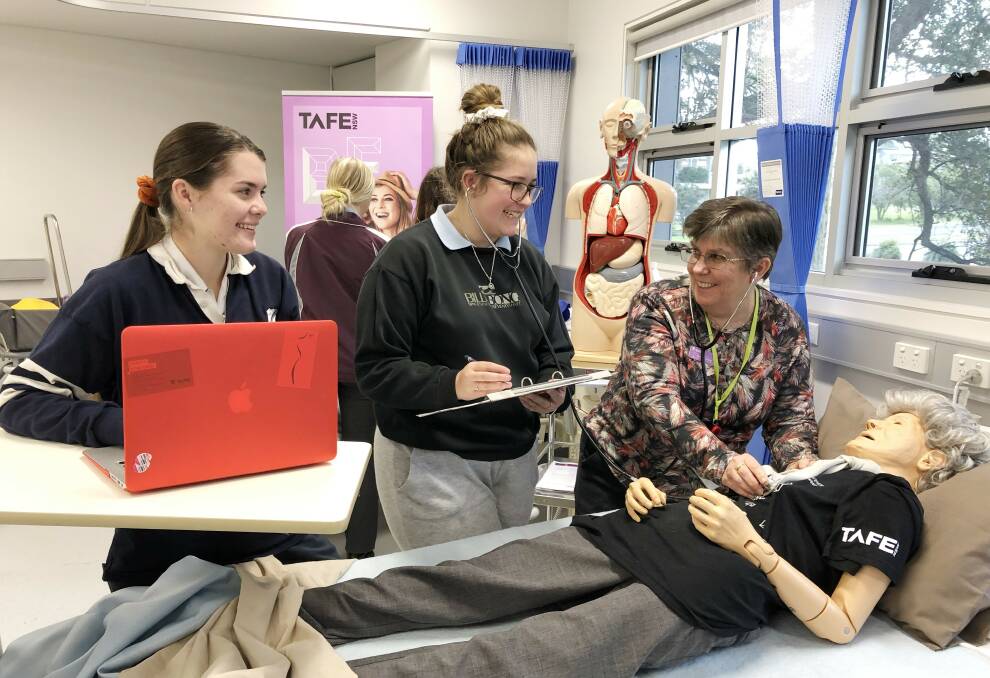 TAFE NSW students Alicia Collison-Gates and Lucy Graham learn hands-on skills from TAFE NSW Teacher Tracey Newcombe. Photo: Adam Wright