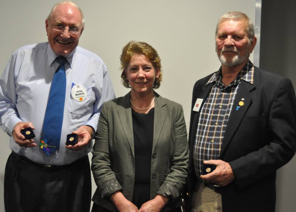 Club member Terry Butler (right) is awarded a saffron pin with Alfred McCarthy (left) by club president Tony Hopkins. Photo: Hannah Sparks