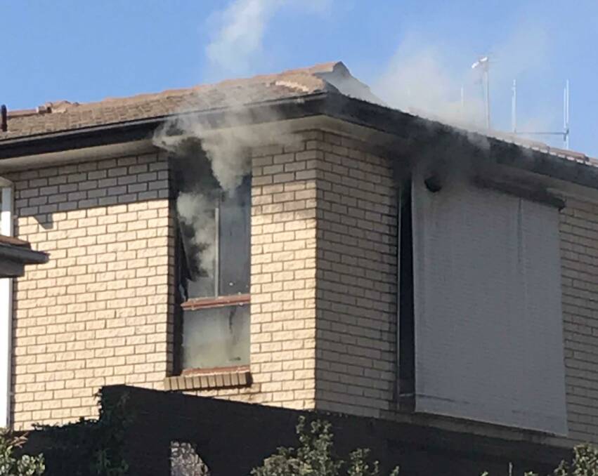 Smoke pours from a bedroom window at the front of the house. Photo: Hannah Sparks