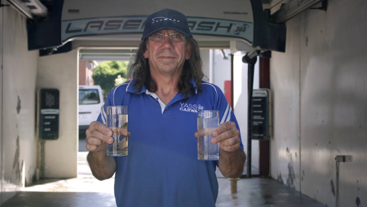 Wayne Pearce at Yass Car Wash shows the colour difference between local tap water (left) and bottled water (right). Photo: Hannah Sparks