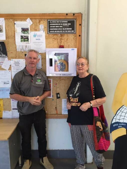 Barry O'Mara and Sue Cassidy install the new AED machine, that could save lives, on the notice board outside of IGA, Yass. Photo: supplied