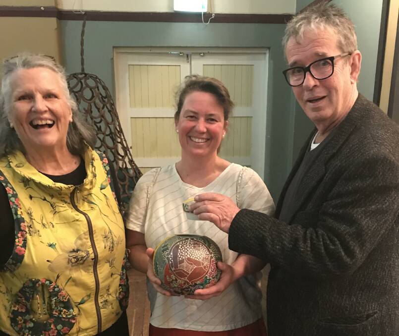 Joanne Searle (middle) holds the patterned ceramic jar made by Janet DeBoos (left) that sold for the top bid of $710 by auctioneer Michael Keighery (right). Photo: Hannah Sparks