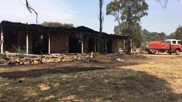 Firefighters return to patrol the house that was destroyed by fire in Murrumbateman. Photo: supplied by Murrumbateman Rural Fire Brigade