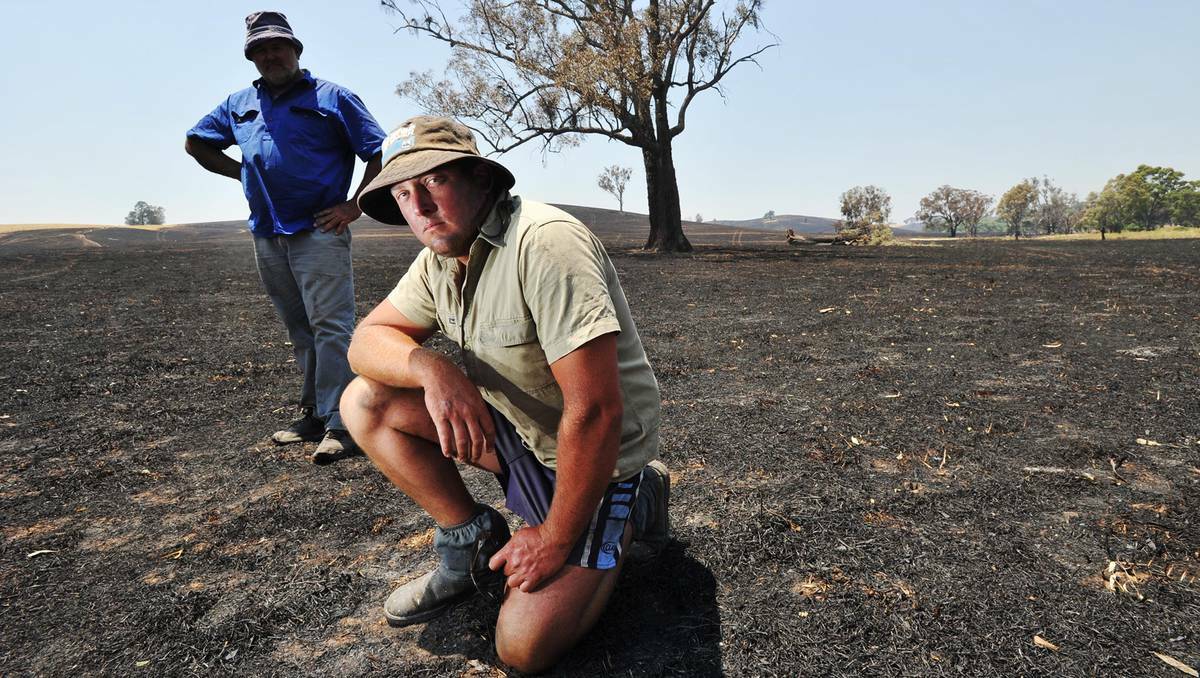 James Douglas (front) and his dad, Les, stand in the burnt land of their Big Springs property. Picture: Oscar Colman