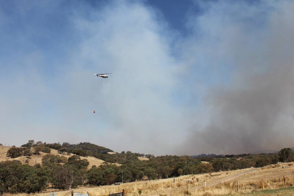A water-bombing helicopter heads into the smoke.